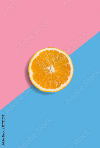 Minimalistic summer fruit tropical composition. Half of juicy fresh orange on light pastel pink and blue background. Citrus fruit refreshment. Vitamins, fresh healthy food concept. Copy space