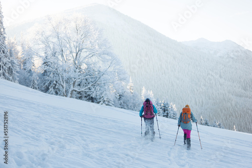 Two women with backpacks walk in snowshoes in the snow © zhukovvvlad
