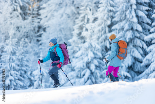 hiking in the mountains on snowshoes. two girls with backpacks go hiking in the snow. Travel and adventure concept.
