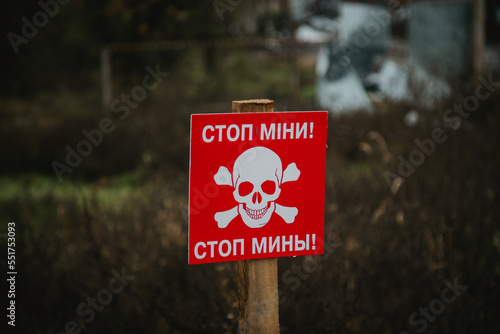 White skull-and-crossbones symbol on a red sign warning of the danger of landmines. Translation: "Stop mines!", war in Ukraine 2022