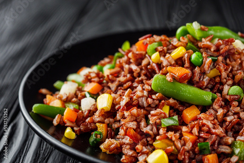 delicious red rice with vegetables on a black wooden rustic background