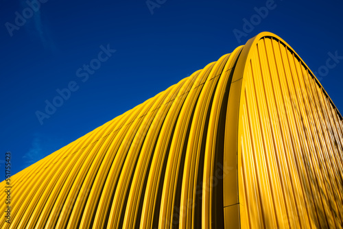 Yellow facade of bent sheet metal with clear blue sky from frog perspective. Yellow and blue contrasting on a sunny bright winters day. Abstract lines and shapes, curves and diagonal structures. photo