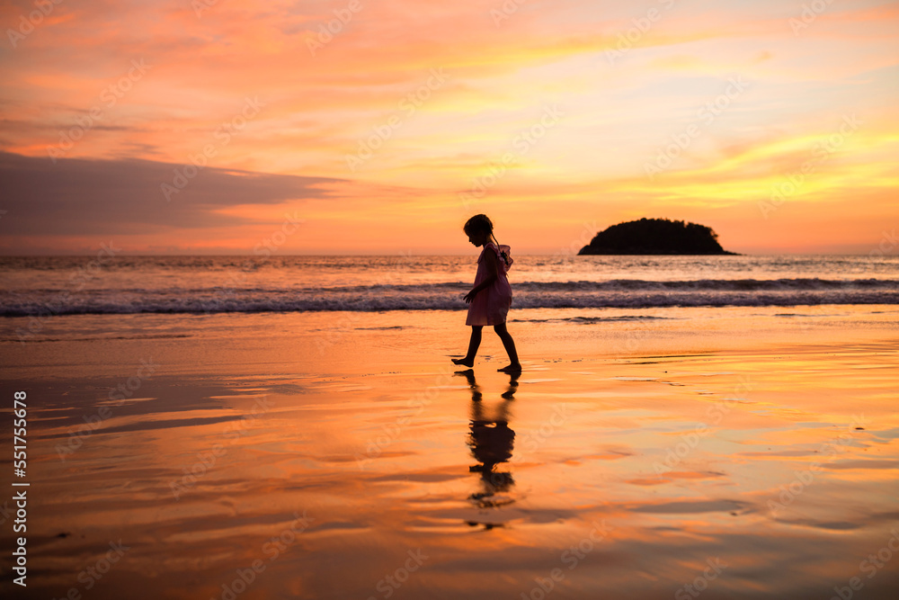 Happy little caucasian girl five years old walking on the tropical beach on sunset