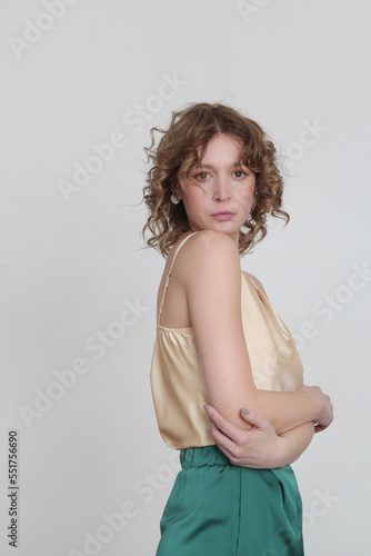 Female model wearing green and beige silk outfit, camisole top and trousers. Classic and simple summer fashion. Studio shot. 