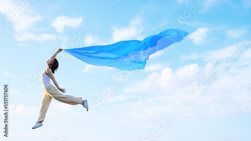 Fotografija 布を羽ばたかせ軽やかに空を飛ぶ女性