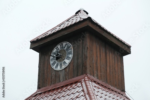 Close up of old urban clock on wooden tower of building.