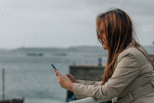 young woman in winter sending a message with the mobile phone © tetxu