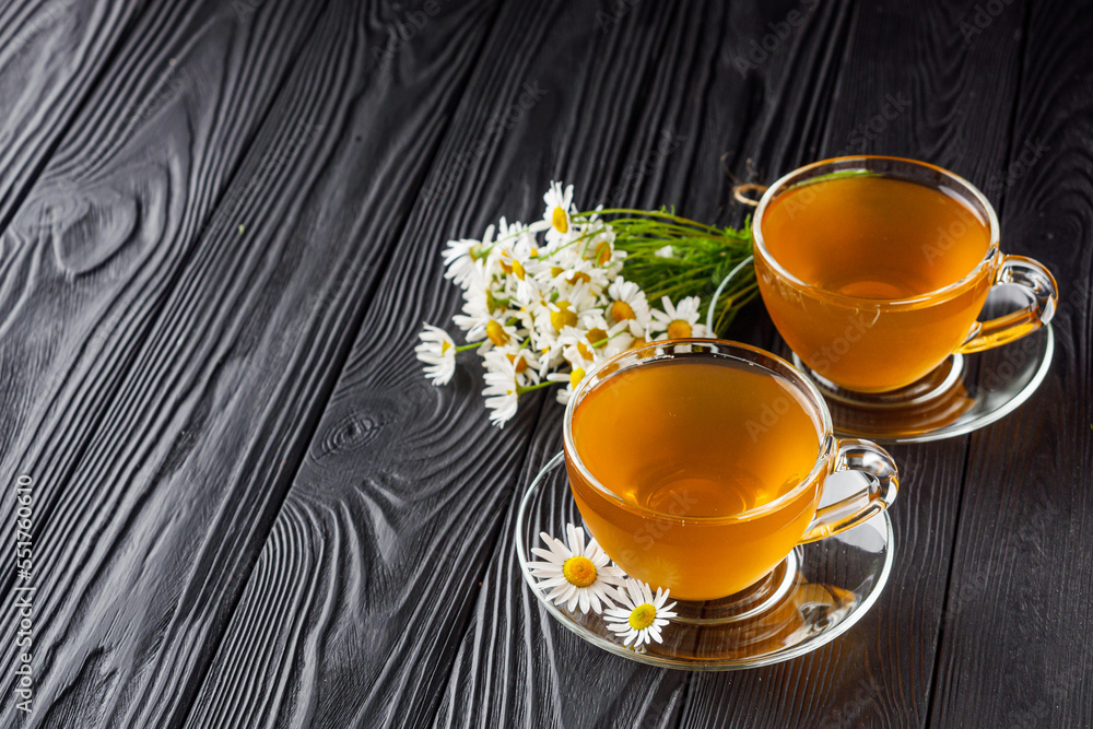aromatic hot chamomile tea on a black rustic wooden background aromatic hot chamomile tea on a black rustic wooden background