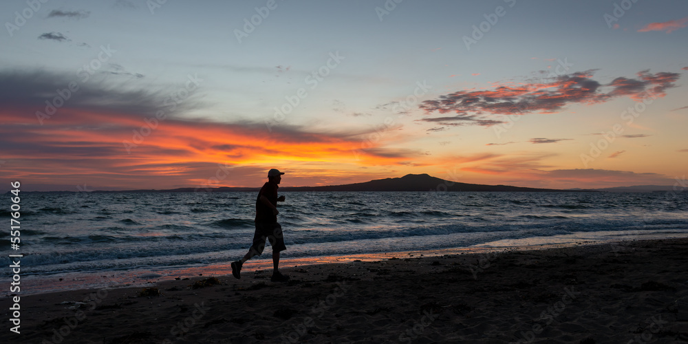 Silhouette image of man running on Milford beach at sunrise, Rangitoto Island in the background, Auckland. Silhouette image of man running on Milford beach at sunrise, Rangitoto Island in the background, Auckland.