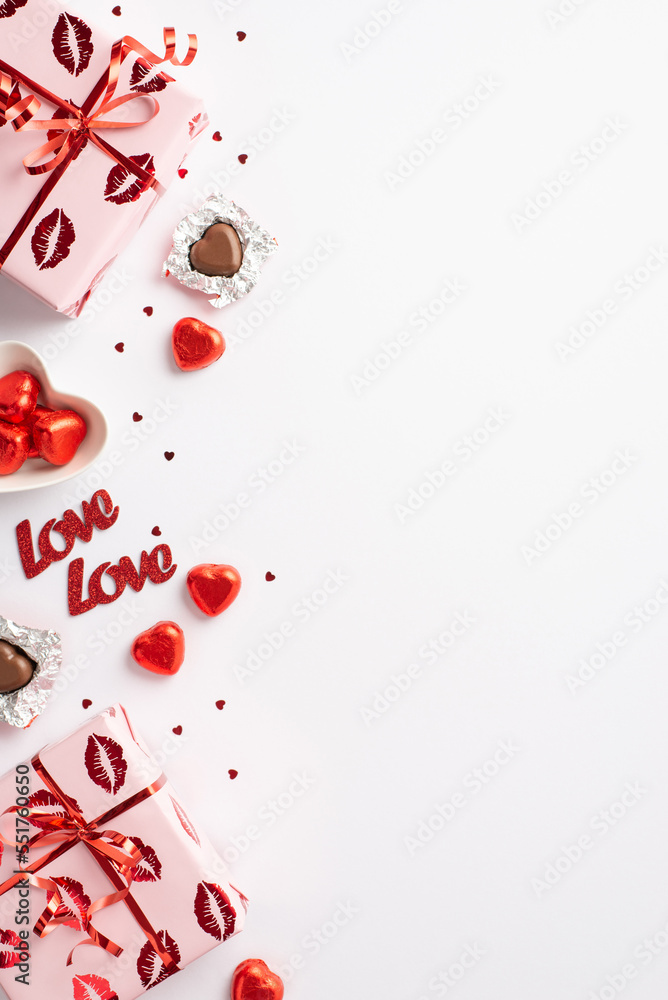 Valentine's Day concept. Top view vertical photo of present boxes plate with heart shaped chocolate candies inscriptions love and confetti on isolated white background with copyspace Valentine's Day concept. Top view vertical photo of present boxes plate with heart shaped chocolate candies inscriptions love and confetti on isolated white background with copyspace