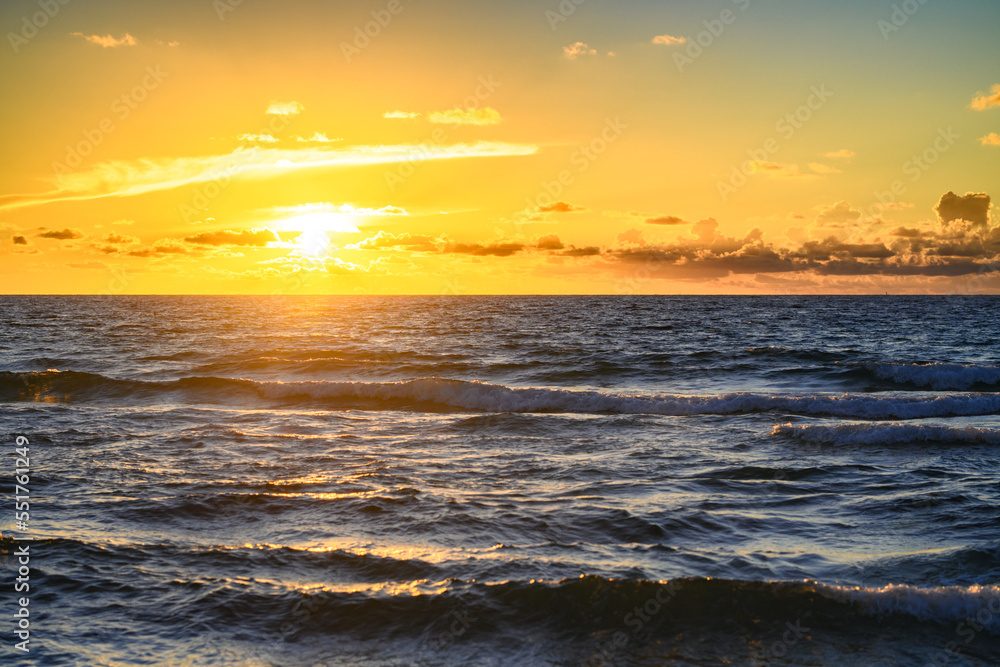 Obraz premium Sunset on tropical beach sea ocean with sunrise clouds. Banner for travel vacation. Scenery sky and reflection rays in water. Dusk, twilight on sea. Tranquil, golden sky background.