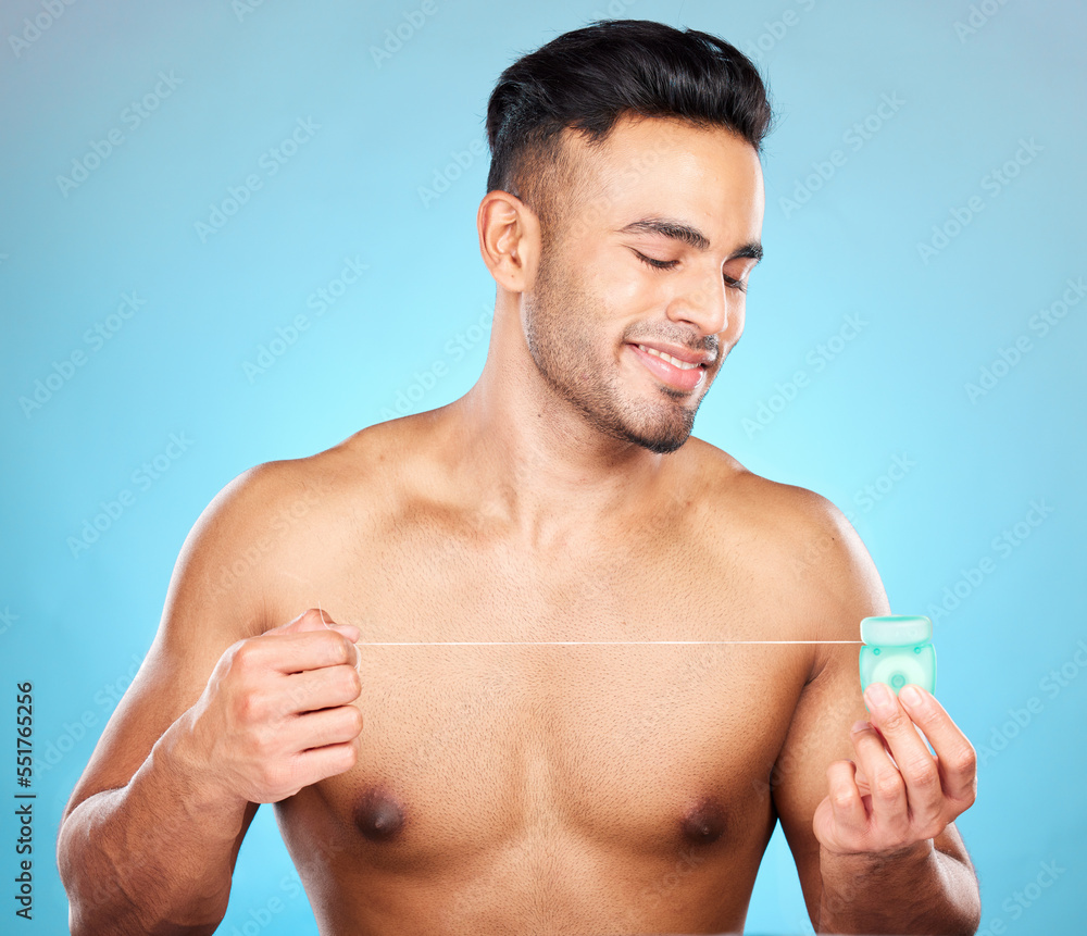 Man, body or dental floss for grooming, mouth hygiene maintenance or plaque removal help on blue background in studio. Smile, happy or flossing model and teeth product in healthcare wellness cleaning Man, body or dental floss for grooming, mouth hygiene maintenance or plaque removal help on blue background in studio. Smile, happy or flossing model and teeth product in healthcare wellness cleaning