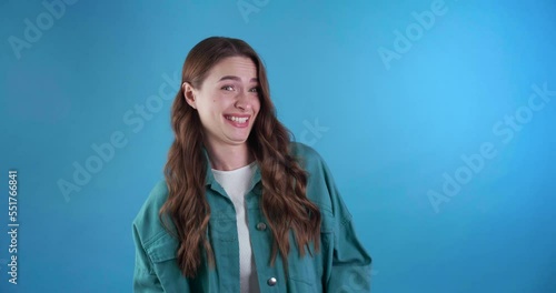 Beautiful young woman laughing and calling someone to laugh together on light blue background