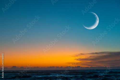 New moon or   rescent above ocean. Half Moon on bright evening sky  space for text