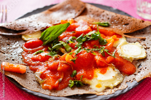 Closeup of French buckwheat crepe Galette with fresh tomato and goat cheese, basil