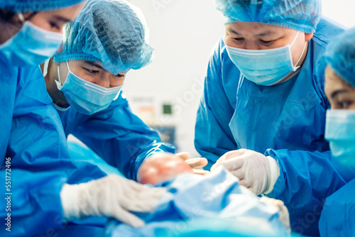 Professional anesthesiologist doctor medical team and assistant is performing baby cesarean section and hold the baby giving birth with surgery equipment in modern hospital operation room