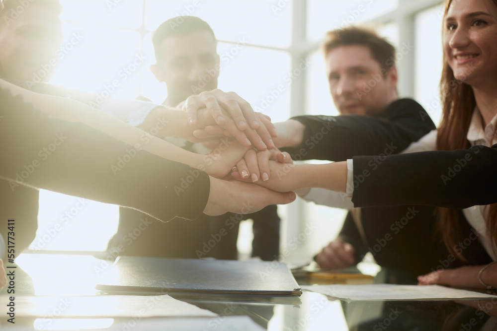 Fototapeta premium group of young business people joining their palms over a work Desk.