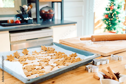 Baking sheet with christmas gingerbread cookies a shape of gingerbread man, christmas tree and star in the kitchen. Baking homemade pastries. Christmas and New Year traditions festive food.