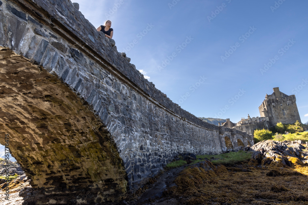 woman on bridge to Eilean Donan Castle near Dornie in Scotland