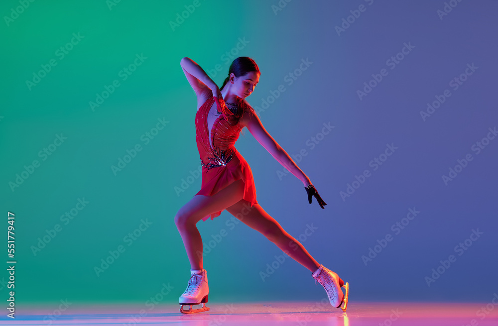 Winter sports. One junior female figure skater in red stage costume showing base figure skating elements, movements isolated over gradient green-blue background in neon light.