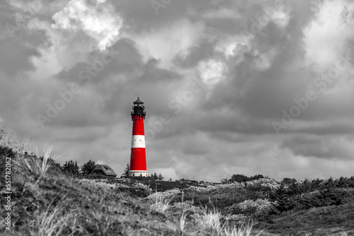 Lighthouse of Hörnum on Sylt island Germany. Red and white tower with dunes. Landmark, sight and guiding light for navigation on north sea. Black and white scenery contrastin with colorful building.