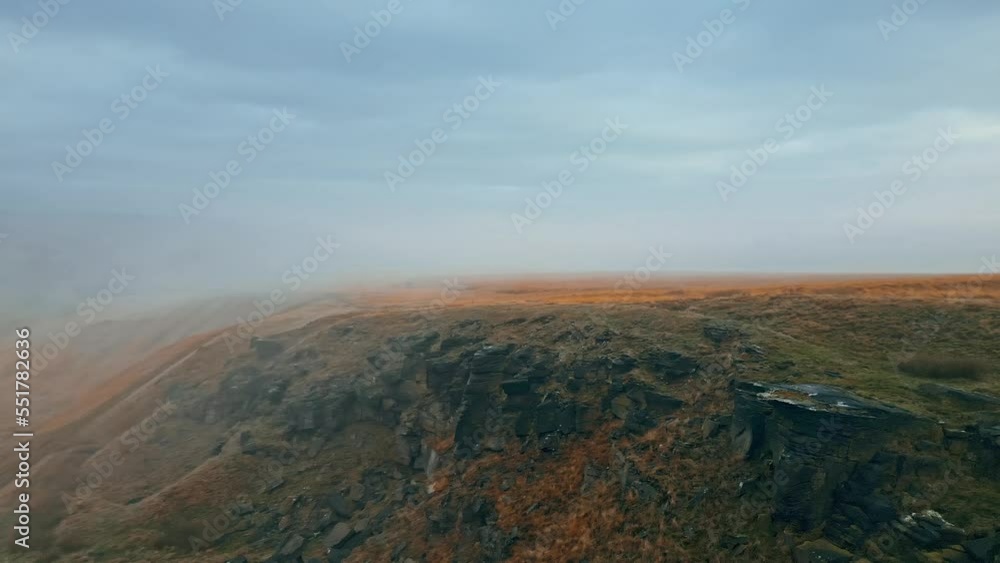 Aerial drone view of morning mists moving slowly over the rugged Pennine hill tops, on a foggy morning, golden hills and beautiful rocky cliffs and moorlands. Flying above the clouds. Aerial drone view of morning mists moving slowly over the rugged Pennine hill tops, on a foggy morning, golden hills and beautiful rocky cliffs and moorlands. Flying above the clouds.