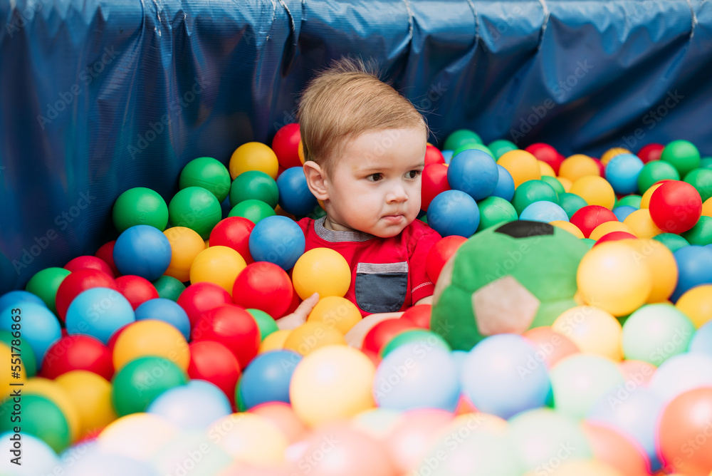 Happy laughing boy 1-2 years old having fun in ball pit in kids amusement park and indoor play center. Activity toys for little kid Happy laughing boy 1-2 years old having fun in ball pit in kids amusement park and indoor play center. Activity toys for little kid