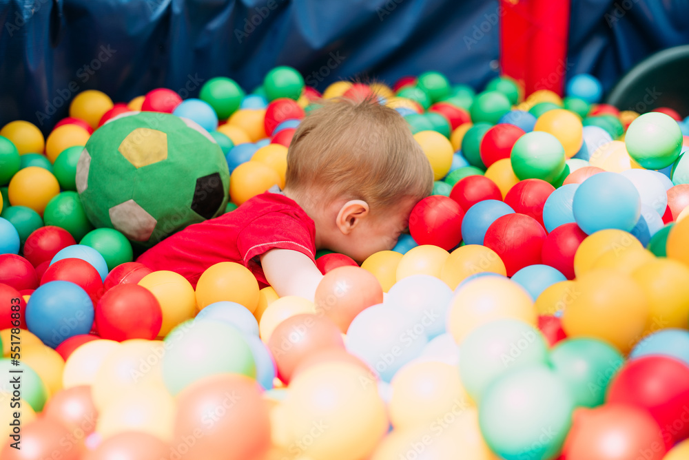 Happy laughing boy 1-2 years old having fun in ball pit in kids amusement park and indoor play center. Activity toys for little kid Happy laughing boy 1-2 years old having fun in ball pit in kids amusement park and indoor play center. Activity toys for little kid