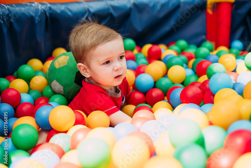 Happy laughing boy 1-2 years old having fun in ball pit  in kids amusement park and indoor play center. Activity toys for little kid © dashamuller