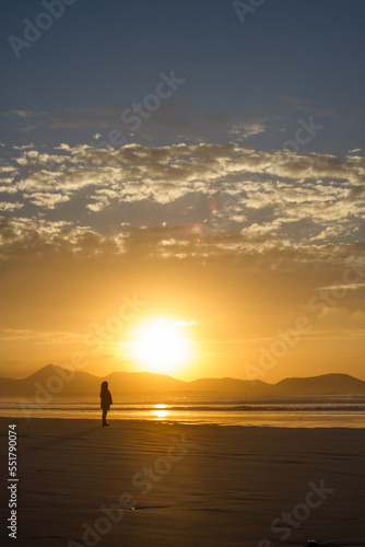 Incredible seascape. Sunset on the beach, clouds golden in the sun. the sun sets behind the mountains. silhouettes of mountains. The ocean washes the sand on the beach. Golden clouds. Background. Lanz