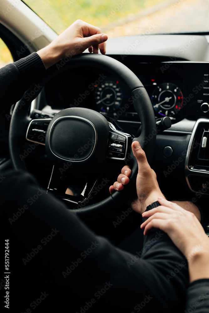 Close up of steering wheel in male driver hand with girlfriend