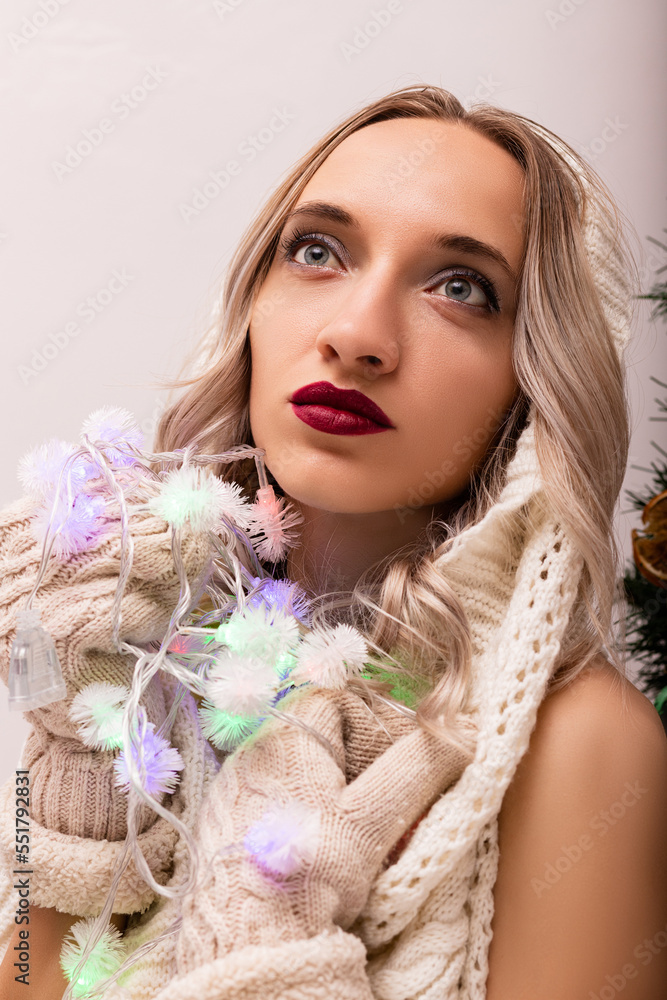 Portrait of a woman in mittens and a Christmas garland near the Christmas tree Portrait of a woman in mittens and a Christmas garland near the Christmas tree