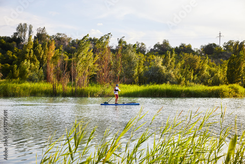 Man ride on SUP board in the mountain lake in city
