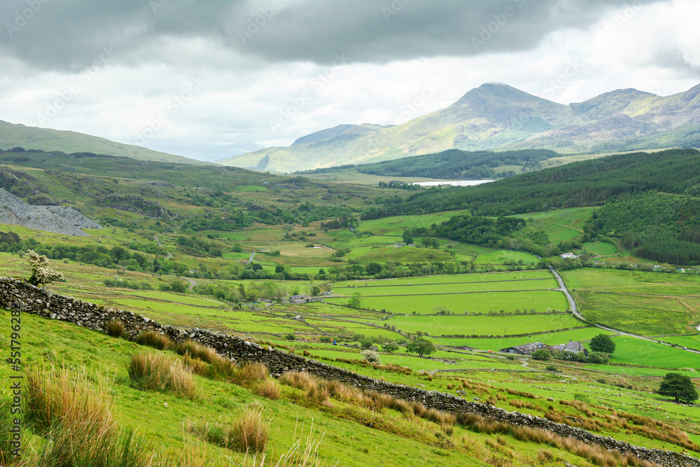 Climbing up mountain range in North Wales, United Kingdom. Rural landsapes, green grass, cloudy sky, selective focus