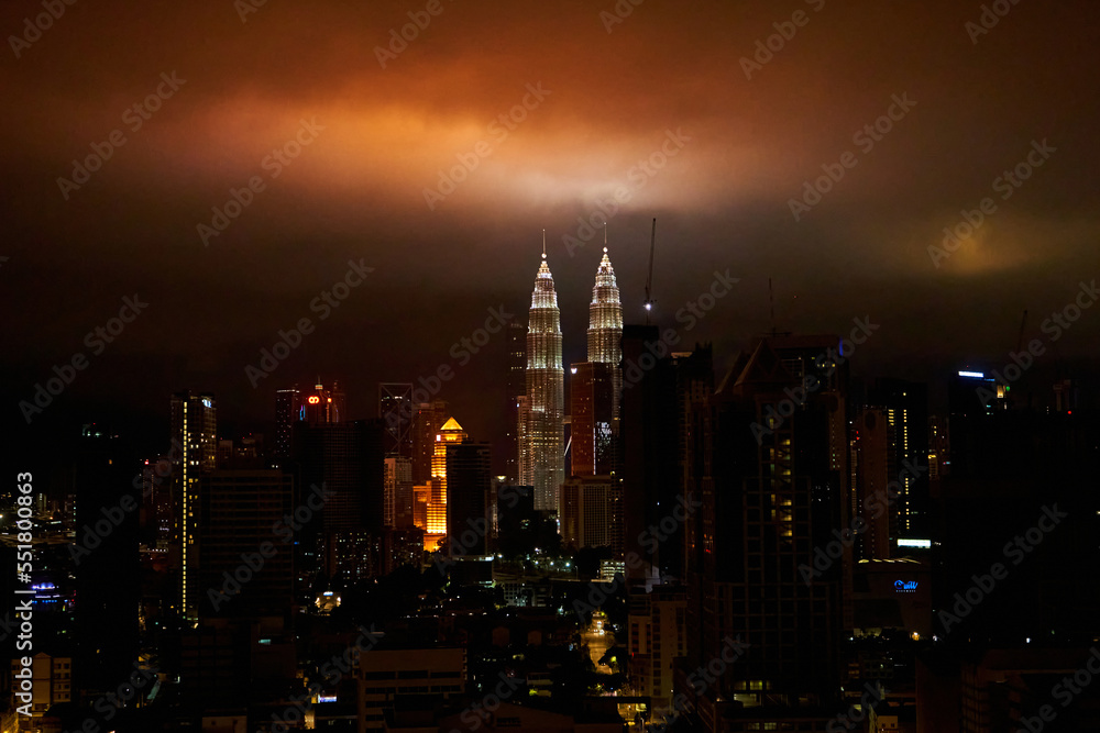 Obraz premium The night landscape of downtown Kuala Lumpur. View of the famous petronas oil company towers. The lighting of the buildings illuminates the clouds