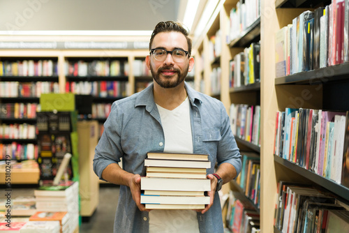 Caucasian man looking at the camera buying a lot of books