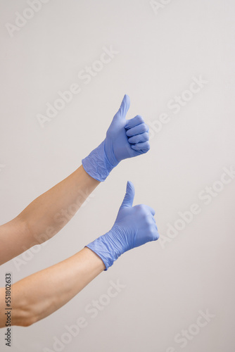 Close up of Doctors or cosmetologist hands in protective gloves showing thumbs up on white background