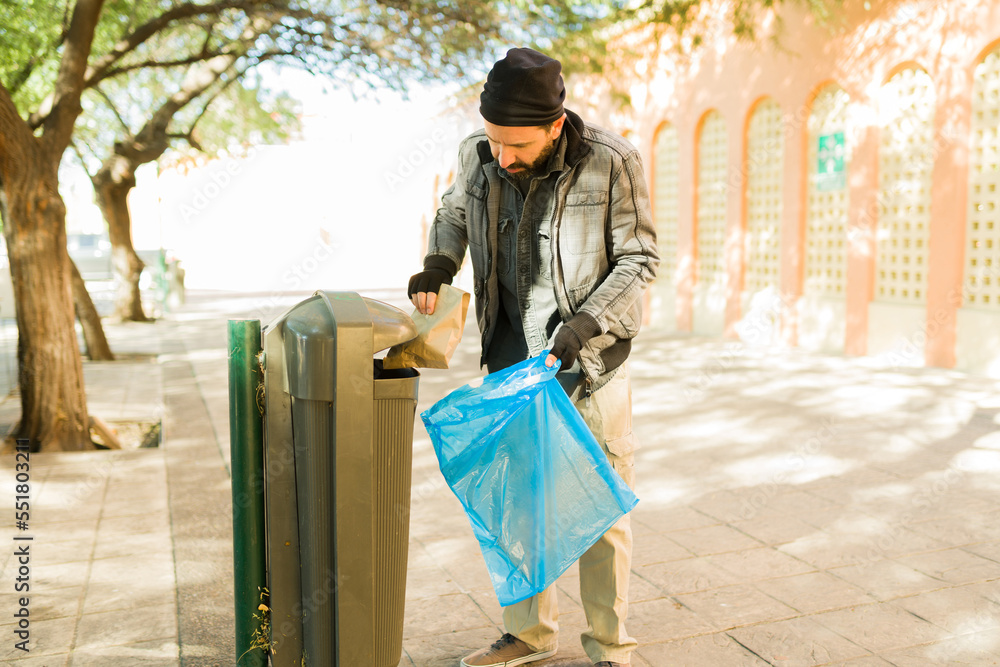 Hungry poor man looking in the trash for food Hungry poor man looking in the trash for food