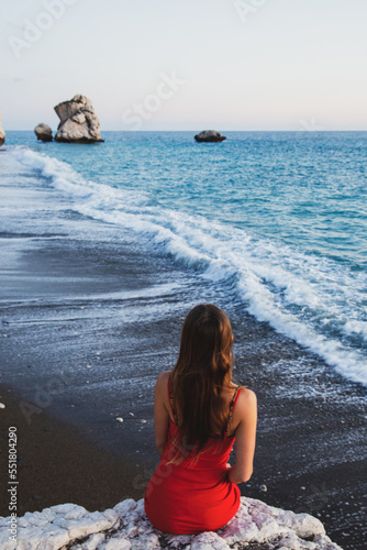 A woman sitting on a rock overlooking Aphrodite's Rocks, Cyprus
 photo