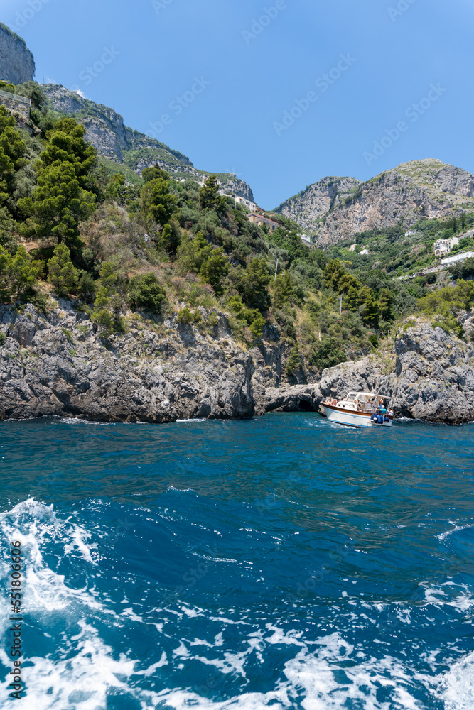 View of the Amalfi coast, captured from a boat on a sunny day.