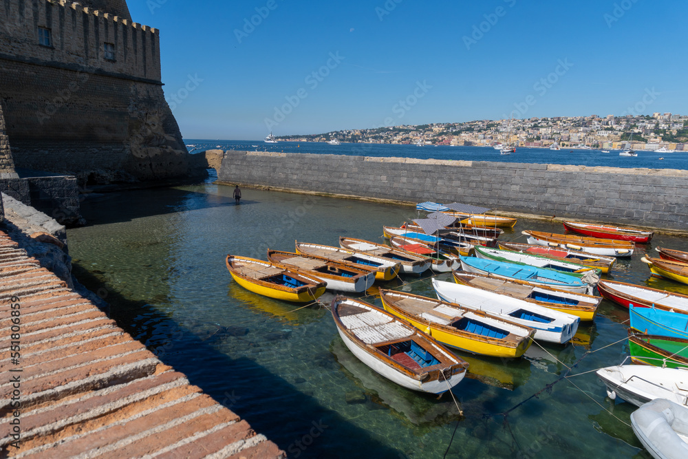 Boats parked in the Castle of the Egg of Naples, with the city on the horizon.