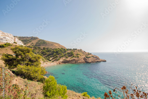 Panorámica de una de las preciosas calas con el agua turquesa de Benidorm bajo un soleado día de otoño con naturaleza al rededor.