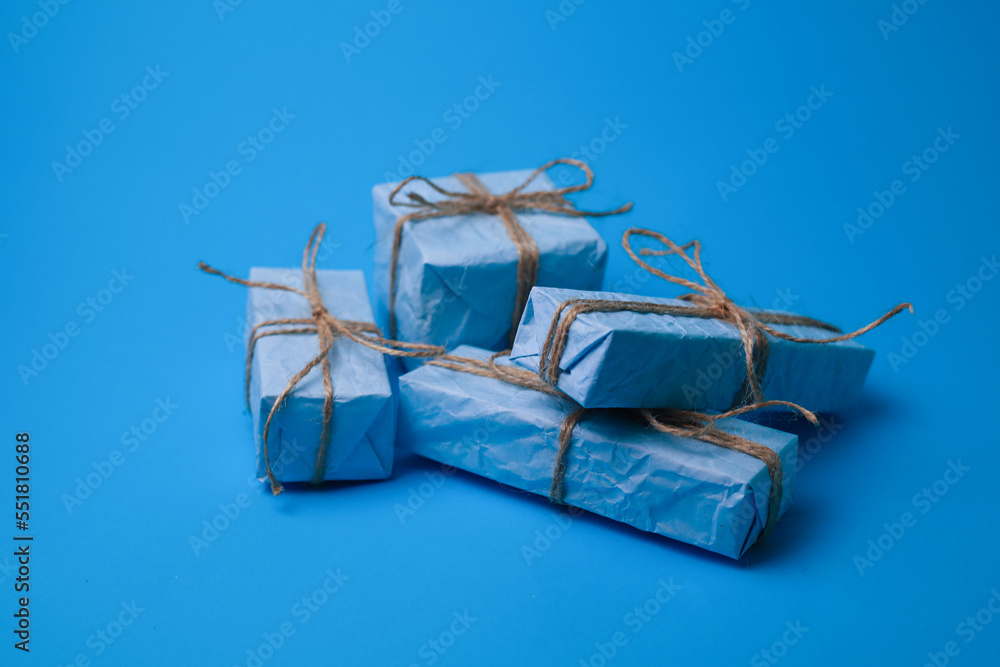 four gifts in blue craft paper tied with twine on a blue background with and without a garland. for calendars cards screensavers invitation labels four gifts in blue craft paper tied with twine on a blue background with and without a garland. for calendars cards screensavers invitation labels