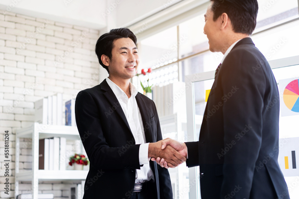 Asian businessmen handshake for the teamwork of business mergers and acquisitions for successful negotiation. Two businessmen shake hands with partners to celebrate a partnership and business deals. Asian businessmen handshake for the teamwork of business mergers and acquisitions for successful negotiation. Two businessmen shake hands with partners to celebrate a partnership and business deals.