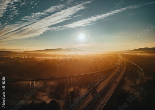 Autumn morning fog over highway with cars covered in fog. Beautiful forest and sun rays. Spotted from above with a drone. Italy Trieste Transportation concept