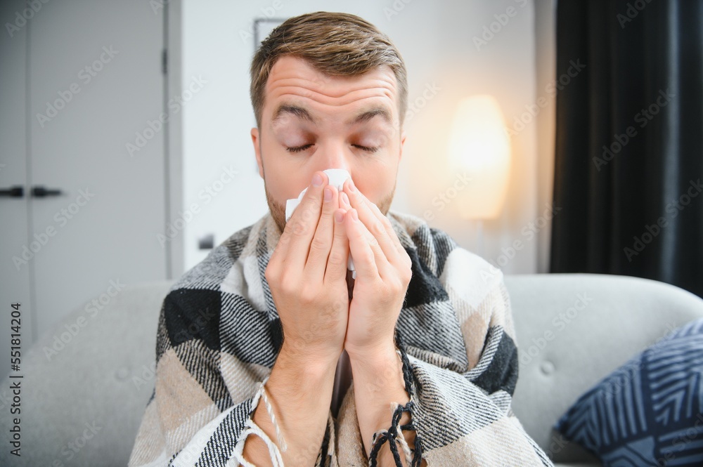 Sick man on sofa at home and blowing nose Sick man on sofa at home and blowing nose