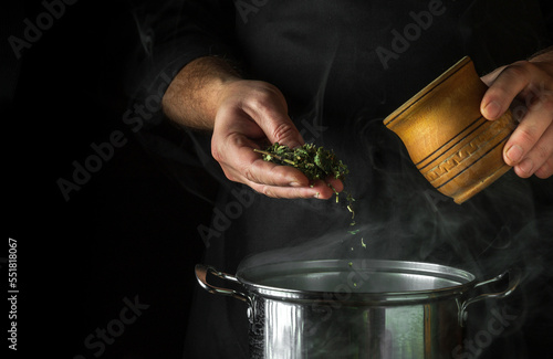 Obraz na plátně The chef adds dried mint to boiling water in a pot to make a healing drink