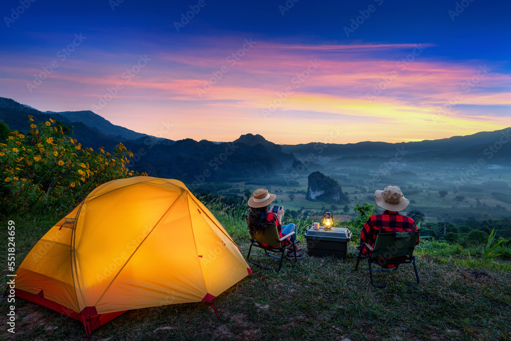 Romantic couple camping outdoors and taking photos with camera while camping at sunrise. Phu Lang Ka, Pha yao province in Thailand.