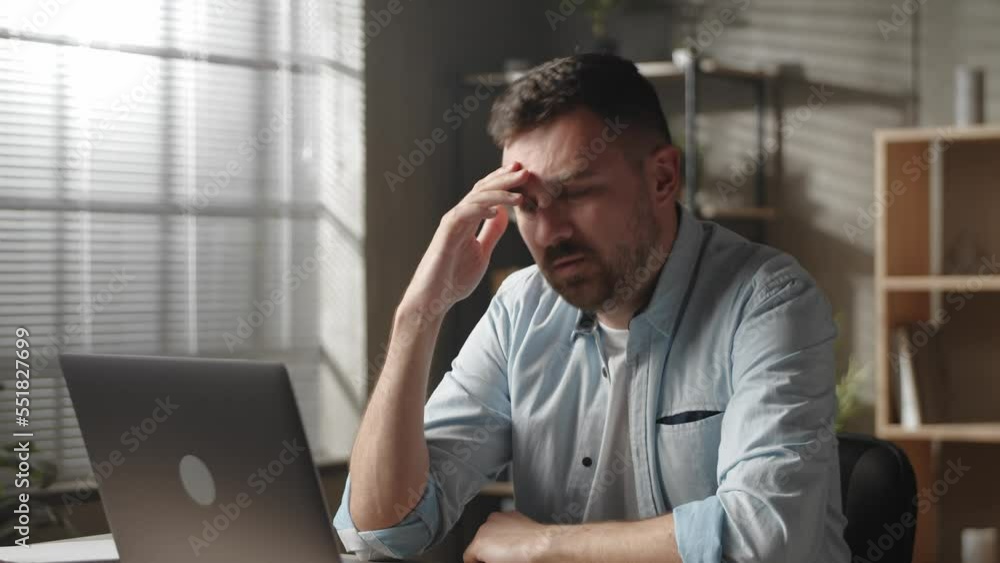 Stressed young male employee manager rubbing forehead, thinking of difficult problem solution, feeling puzzled or overwhelmed working on computer at modern home office Stressed young male employee manager rubbing forehead, thinking of difficult problem solution, feeling puzzled or overwhelmed working on computer at modern home office