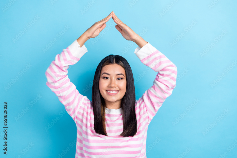 Photo of sweet cheerful young lady wear striped sweater showing arms roof isolated blue color background
